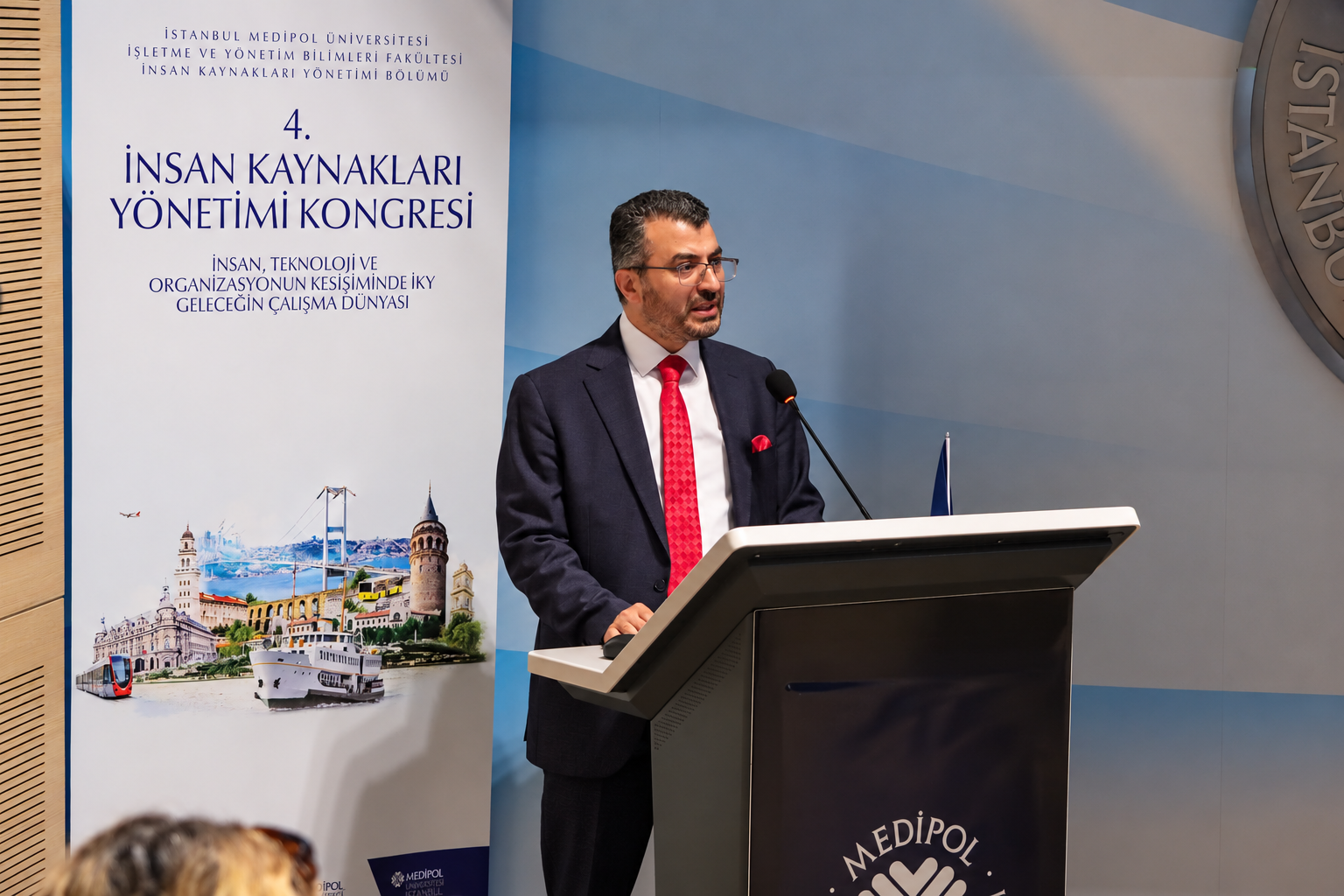 Man speaking at podium beside flag